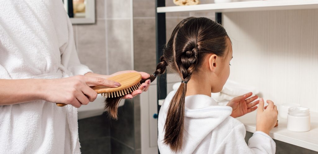 أمّ تُسرّح طرف ظفيرة ابنتها