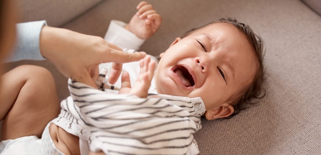 طفل يبكي أثناء محاولة والدته في تلبيسه