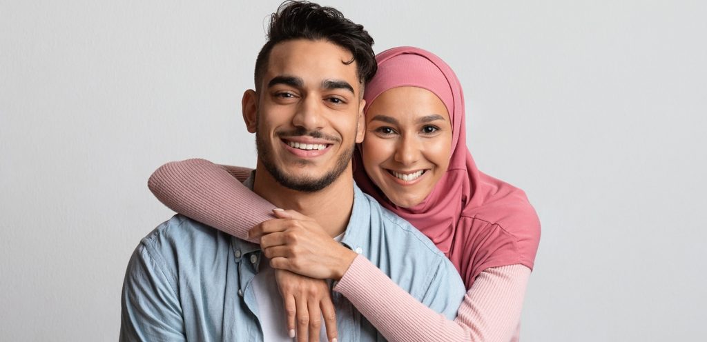 امرأة محجّبة تُعانق زوجها من الخلف