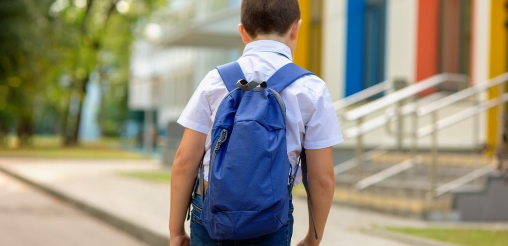 طفل يضع شنطة المدرسة على ظهره ويمشي