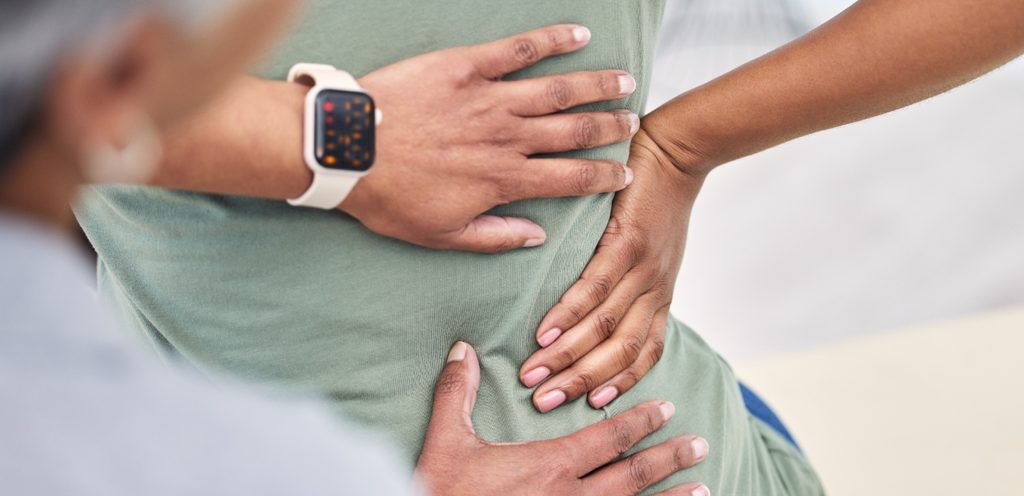 امرأة تشعر بالألم تضع يدها على خصرها الأيمن وامرأة أخرى تضع يديها على المكان نفسه