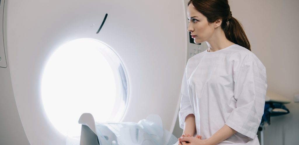 امرأة تجلس بجدّيّة أمام آلة الأشعّة المقطعيّة