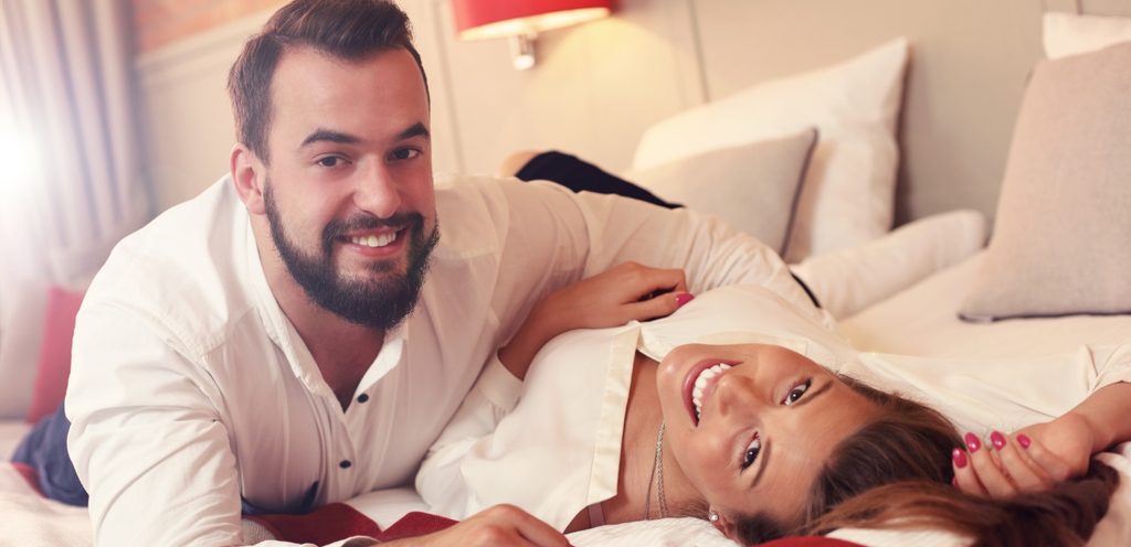 زوجان مستلقيان على السرير يبتسمان