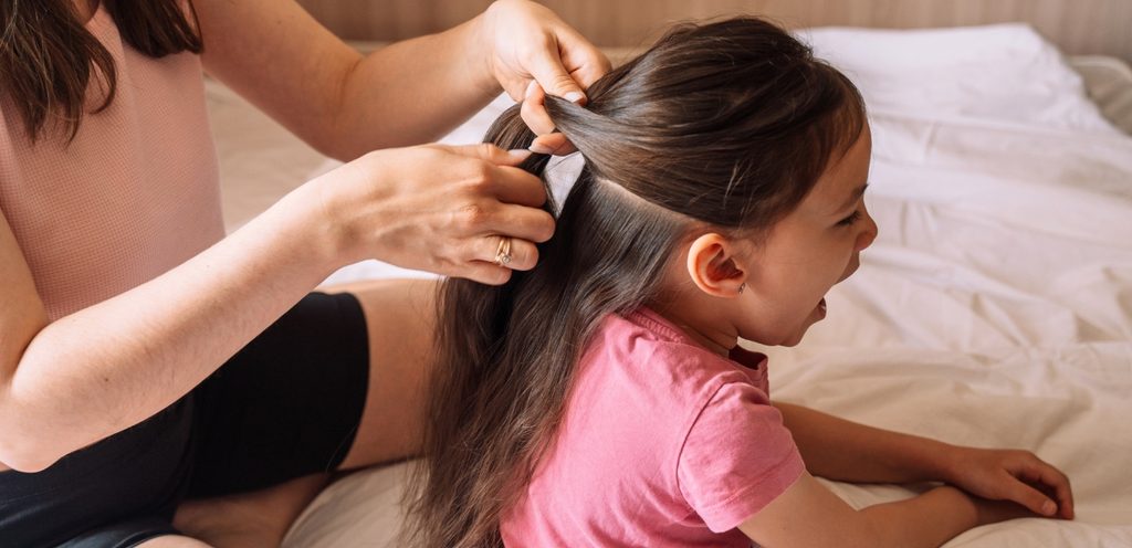 أمّ تسرّح شعر ابنتها على السرير