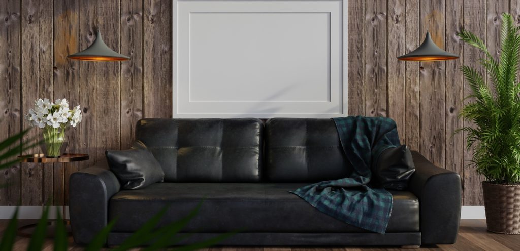 أريكة سوداء أمام خلفيّة خشبيّة وبجانبها نباتات وزهور