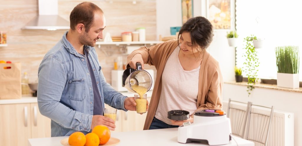 امرأة تسكب لزوجها عصير في كوب يحمله في يده