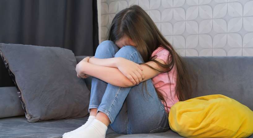طفلة حزينة تجلس على كنبة
