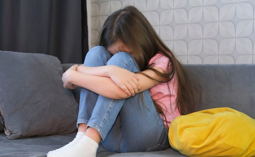 طفلة حزينة تجلس على كنبة