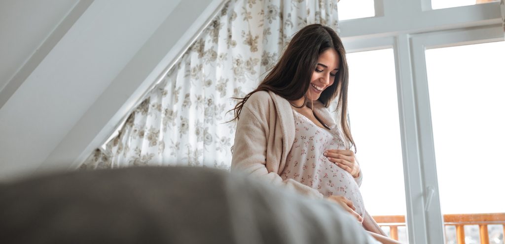 امرأة حامل تضع يدها على بطنها وتبتسم