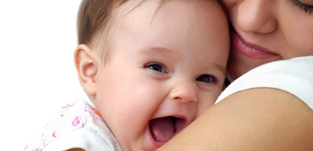 أمّ مبتسمة تحمل طفلها السعيد وهو يفتح فمه