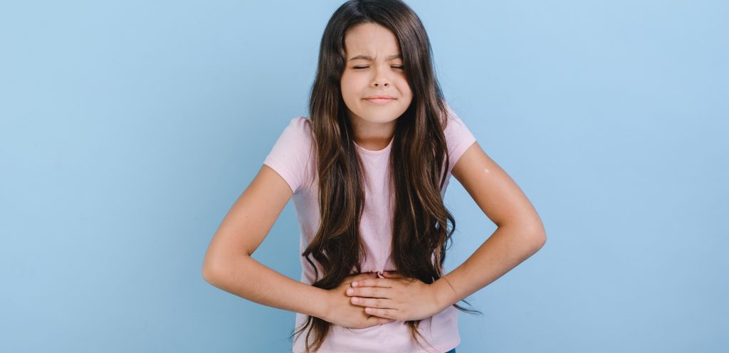 فتاة صغيرة تضع يديها على بطنها وتشعر بالألم