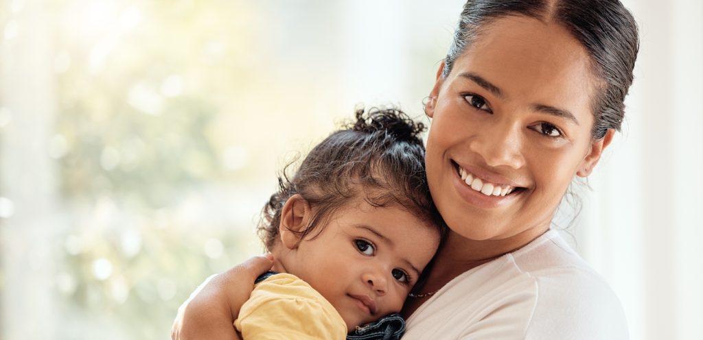 أمّ تحمل رضيعتها وتبتسم