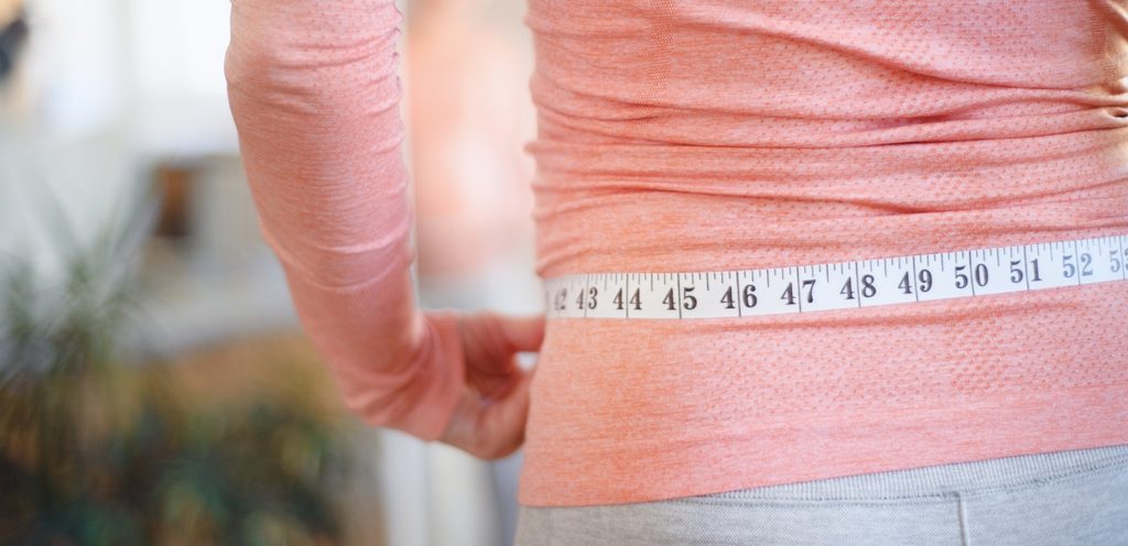 امرأة حول خصرها شريط قياس