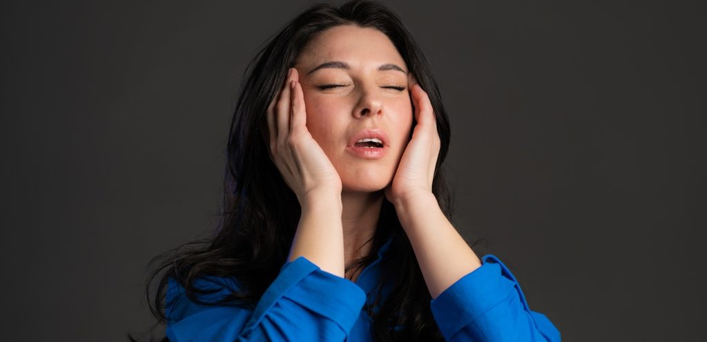 امرأة تغمض عينيها وتضع يديها على رأسها