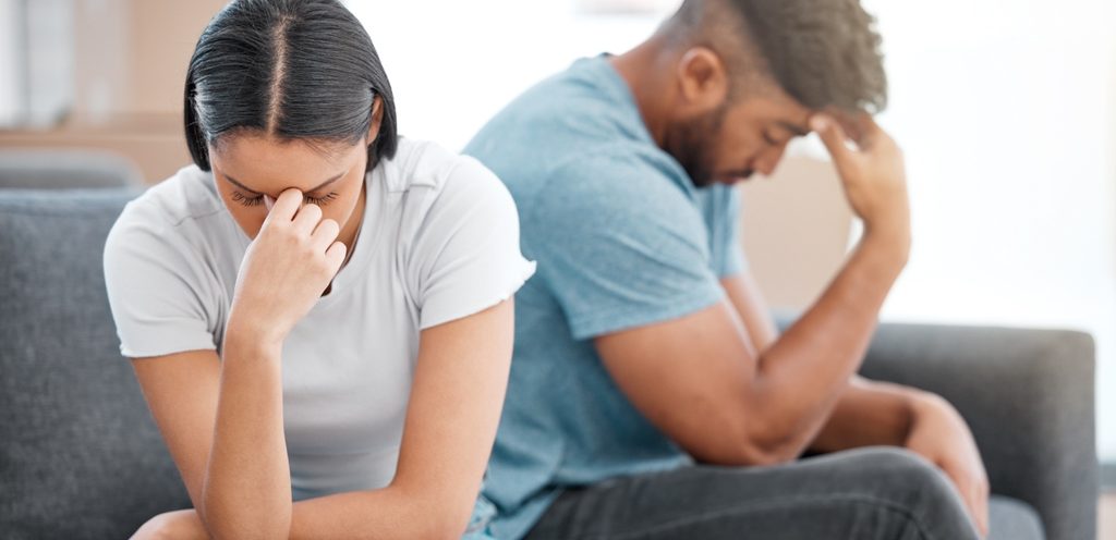 زوجان متخاصمان يجلسان بعكس بعضهما البعض ويضع كلّ منهما يده على رأسه بحزن