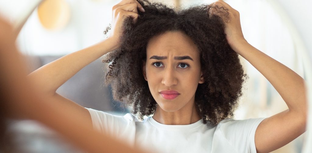 شابّة تمسك شعرها وتنظر إلى المرآة