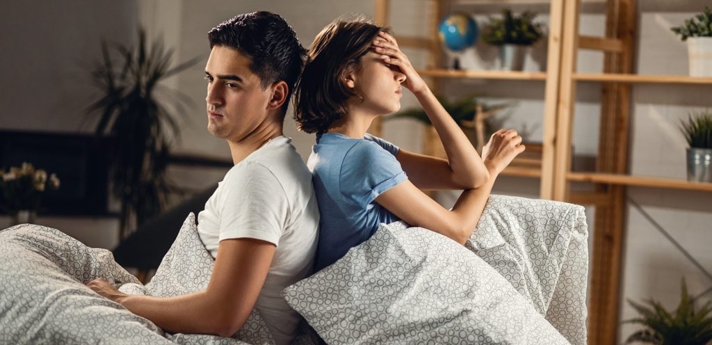 زوجان يجلسان على السرير بعكس بعضهما