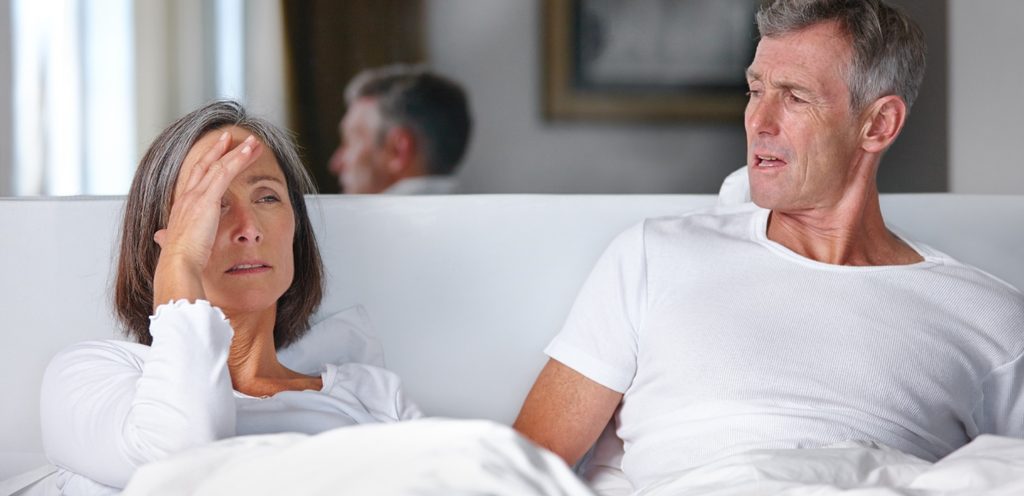 زوجان بالغان متخاصمان يجلسان في السرير