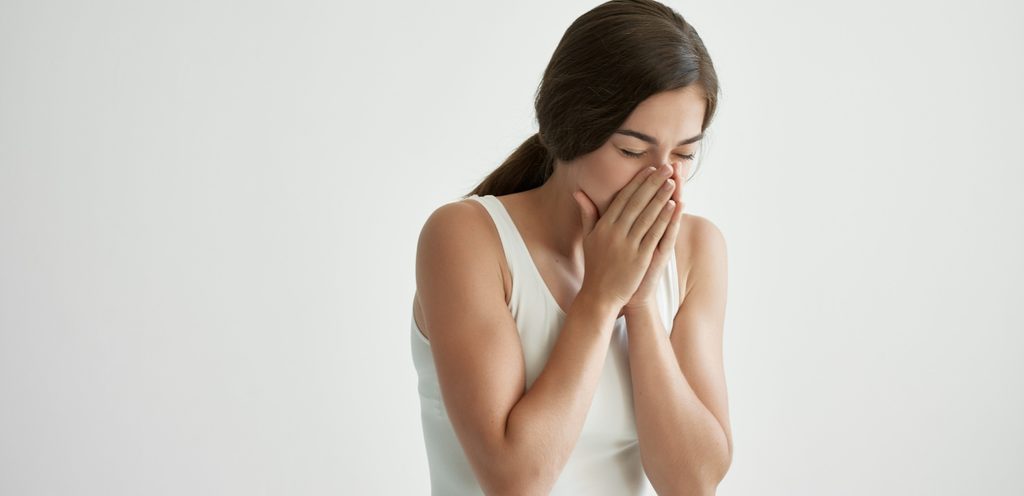 شابة تغمض عينيها وتضع يديها على أنفها وفمها