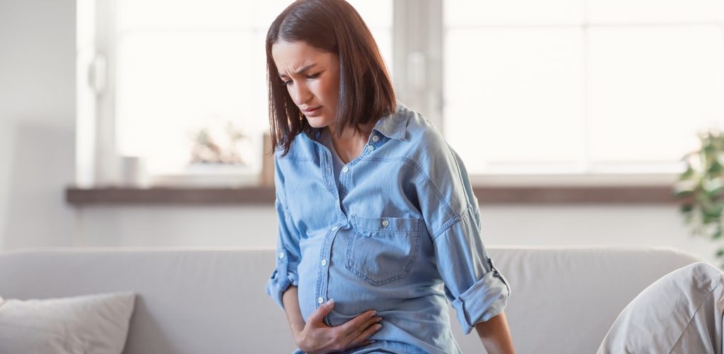 امرأة حامل تضع يدها على بطنها وتشعر بالألم