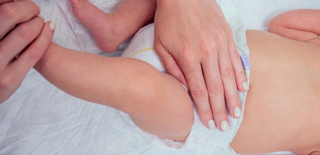 أمّ تضع يدها على حفاضة رضيعها