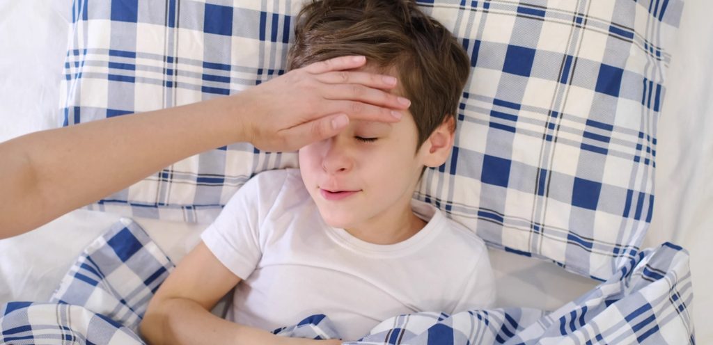 طفل نائم في السرير ووالدته تضع يدها على رأسه