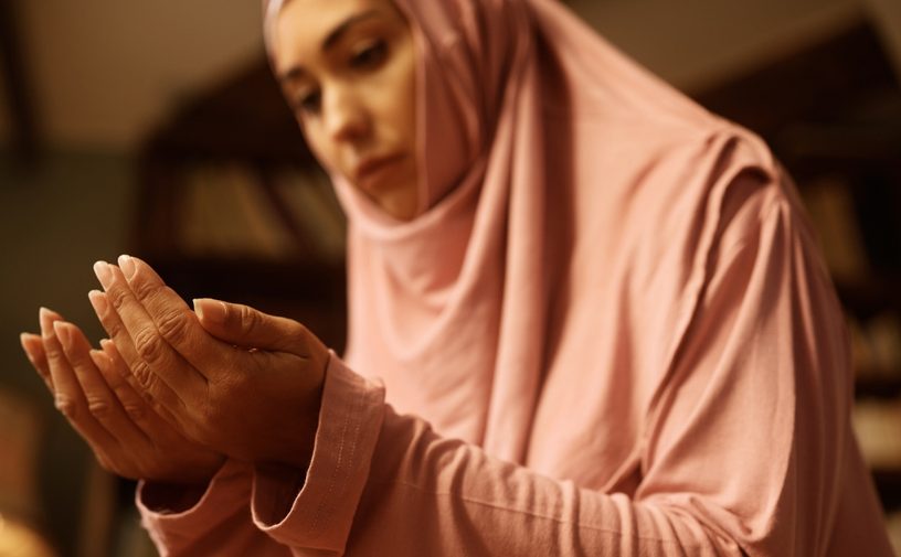 امرأة ترتدي ملابس الصلاة وتدعو اللهِ