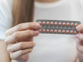 امرأة تحمل بيدها لوحة حبوب منع الحمل