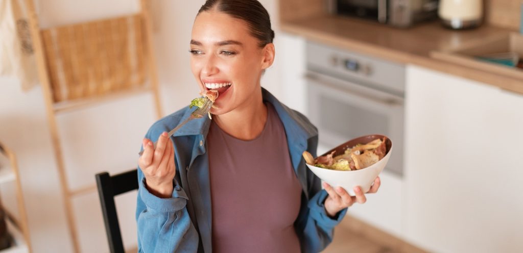 امرأة مبتسمة تمسك طبقًا وتأكّل