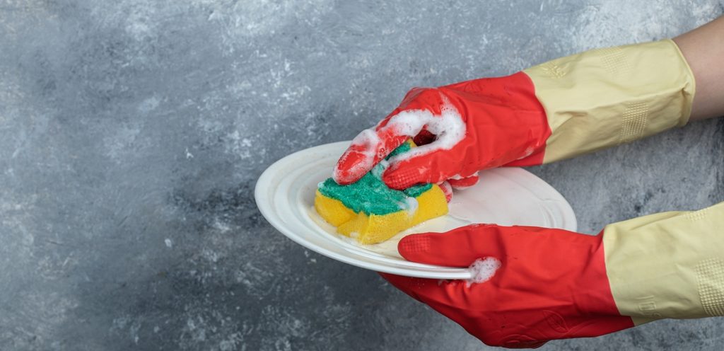 يد امرأة تنظف الصحن بالإسفنجة