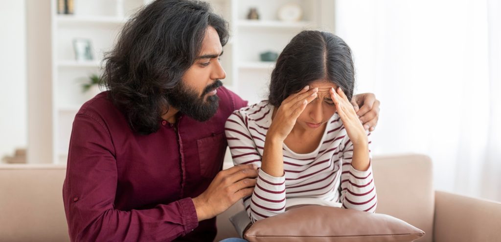 امرأة حزينة وبجانبها رجل يحاول أن يواسيها