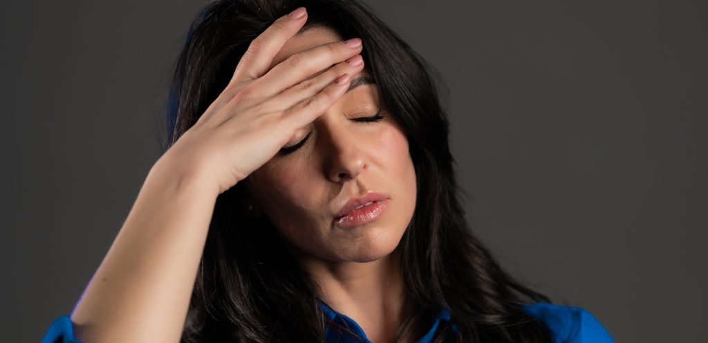 امرأة تغمض عينيها وتضع يدها على رأسها
