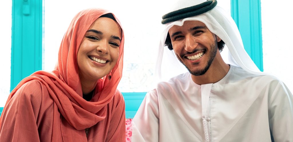 زوجان عربيان مبتسمان يجلسان جنبًا إلى جنب