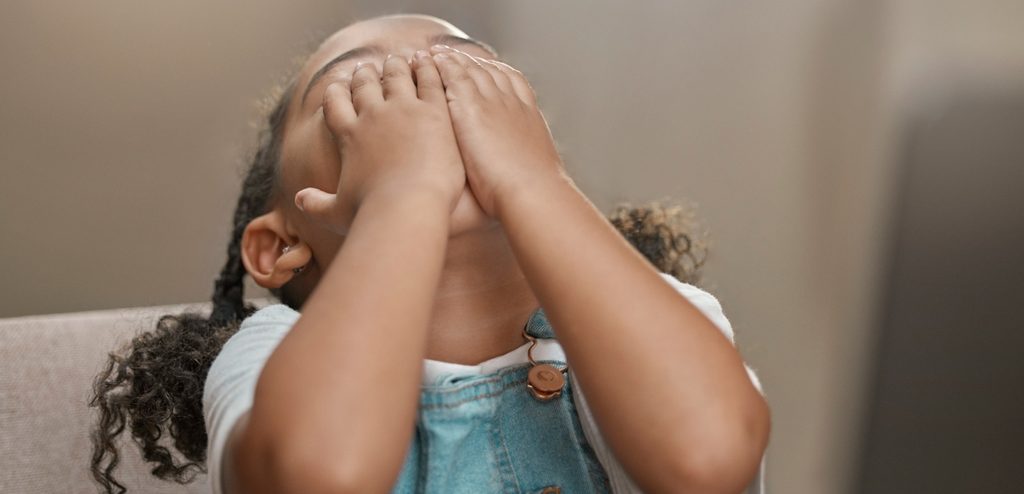 طفلة تضع يديها على عينيها وترفع رأسها لأعلى