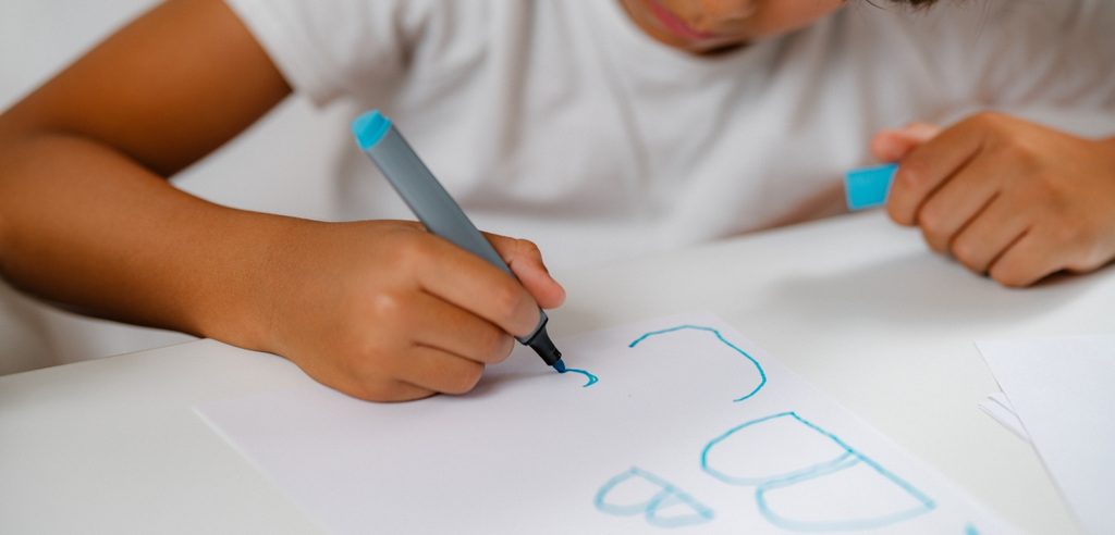 طفل يكتب على الورقة باللون الأزرق