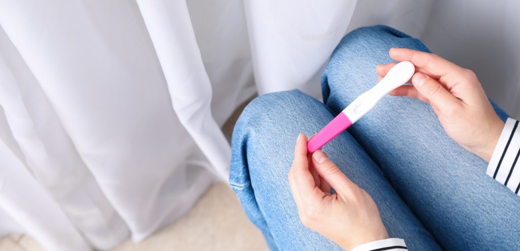 امرأة جالسة تمسك اختبار حمل