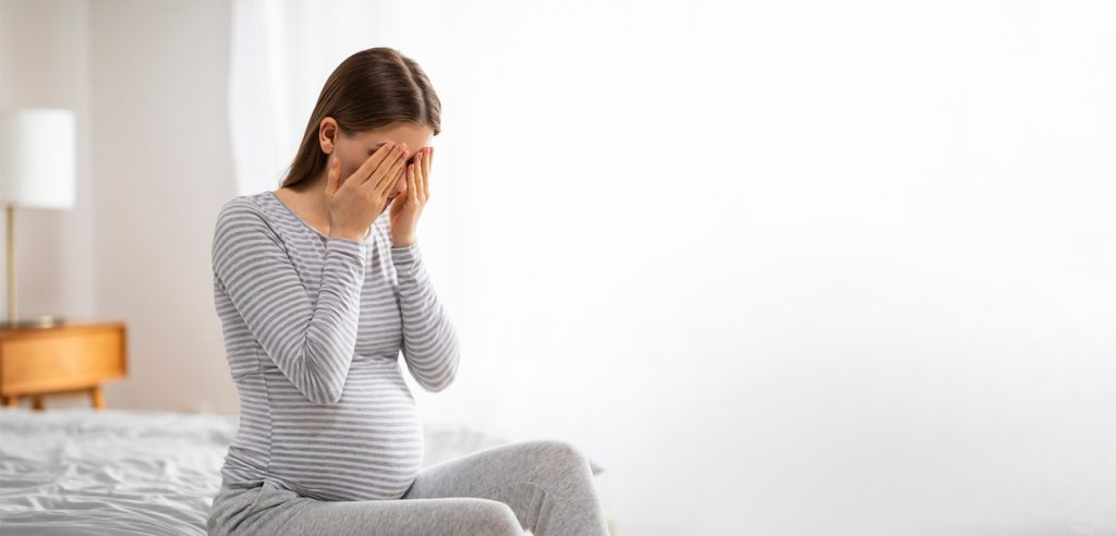 امرأة حامل تضع يديها على وجهها حزينة