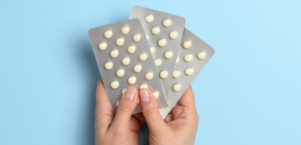 امرأة تمسك بين يديها شرائط دواء