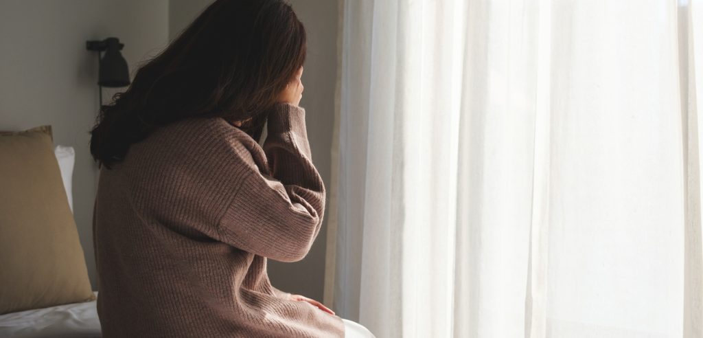 امرأة حزينة تجلس على السرير