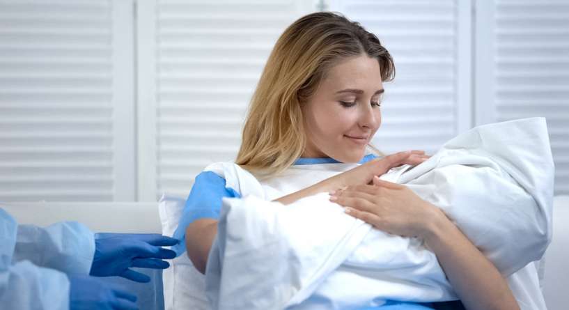 امرأة تحمل طفلها بعد الولادة