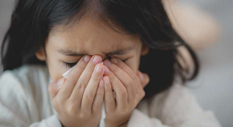طفلة تضع يديها فوق أنفها