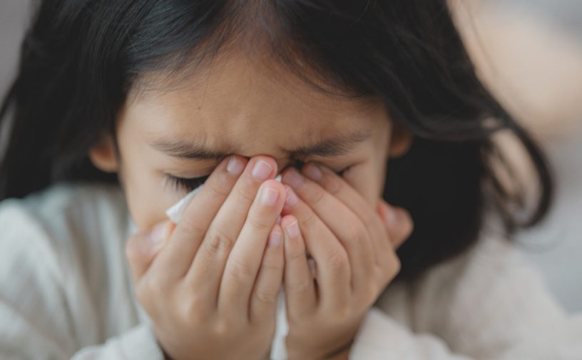 طفلة تضع يديها فوق أنفها