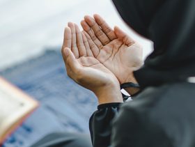 امرأة ترفع يديها بالدعاء