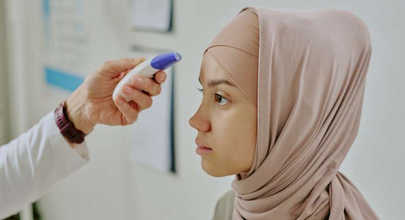 طبيب يقيس درجة حرارة مريضته