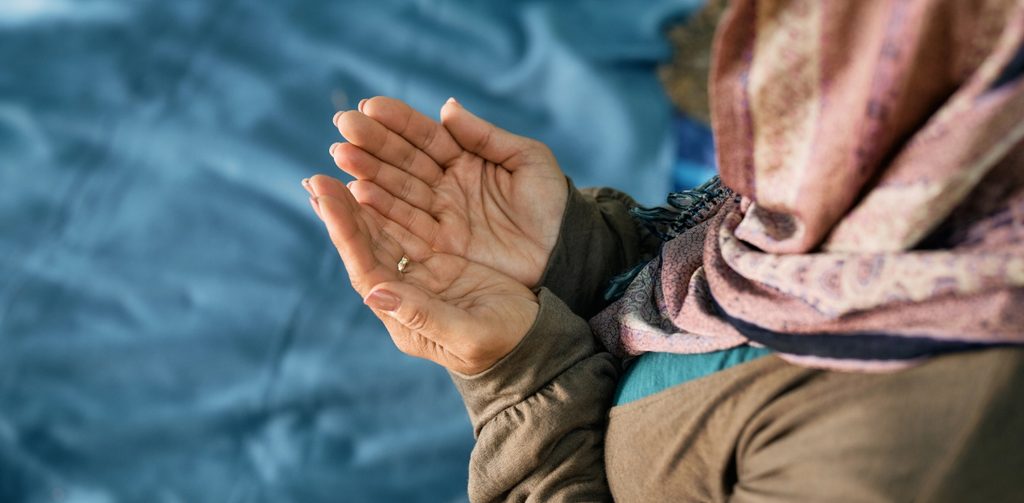 امرأة مسلمة ترفع يديها للدعاء