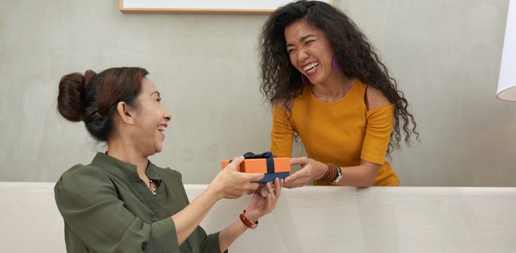 امرأة تقدّم هديّة لامرأة أخرى وكلاهما سعيدتين