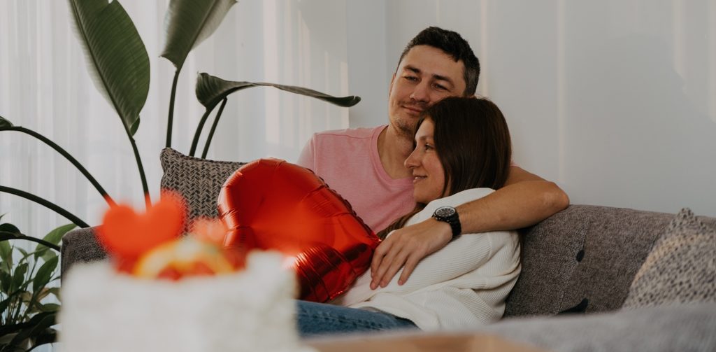 زوج يعانق زوجته ويمسك بالون أحمر