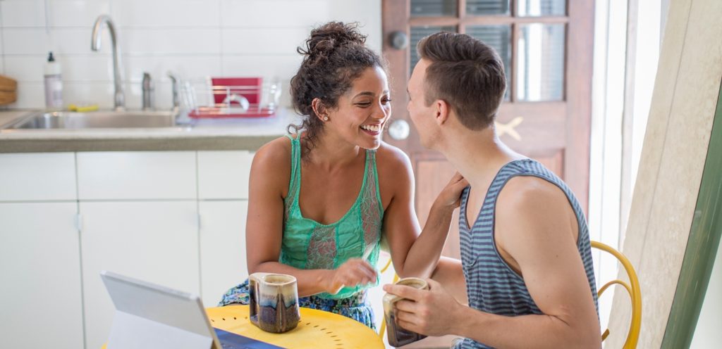 زوجان سعيدان ينظران إلى بعضهما البعض بسعادة ويمسكان كوبين