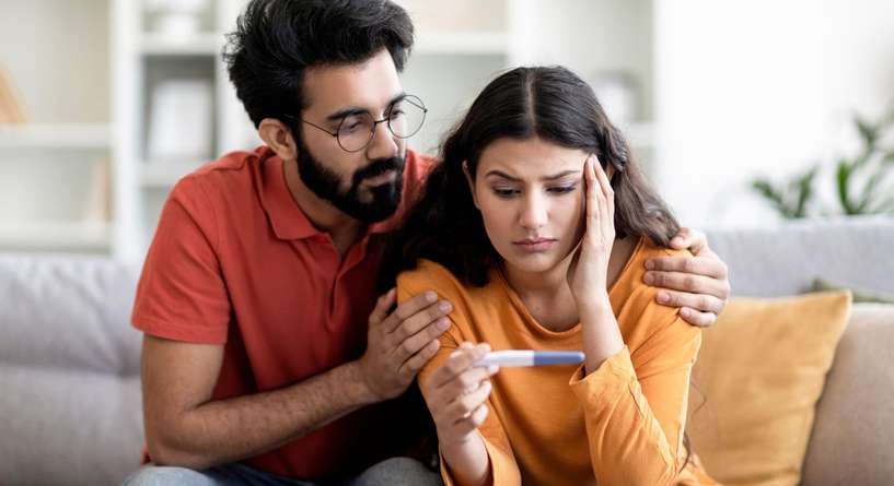 زوجان ينظران إلى اختبار الحمل بحزن