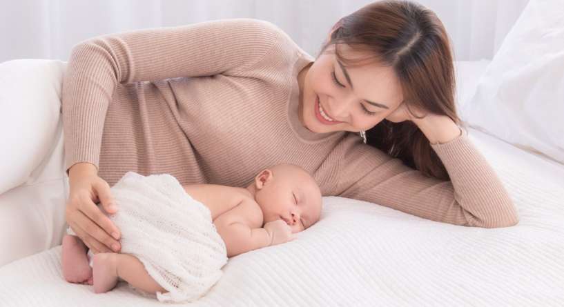 أم تجلس قرب رضيعها